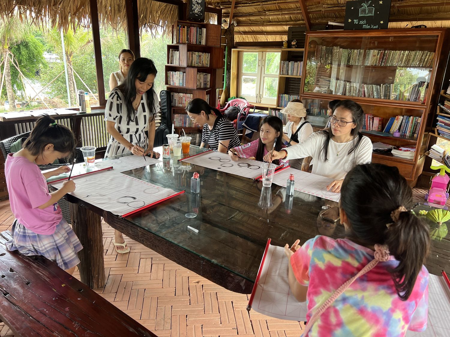 Chòi gỗ mái tranh của Duyên Quơ với bàn dài và tủ sách